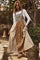 woman wearing a long patchwork dress with floral and striped patterns over a white long sleeve top and wooden sandals