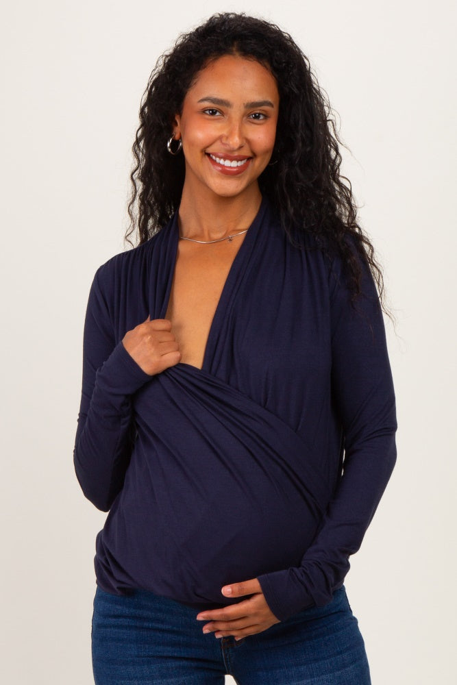 woman wearing a navy blue maternity wrap top and holding her baby bump