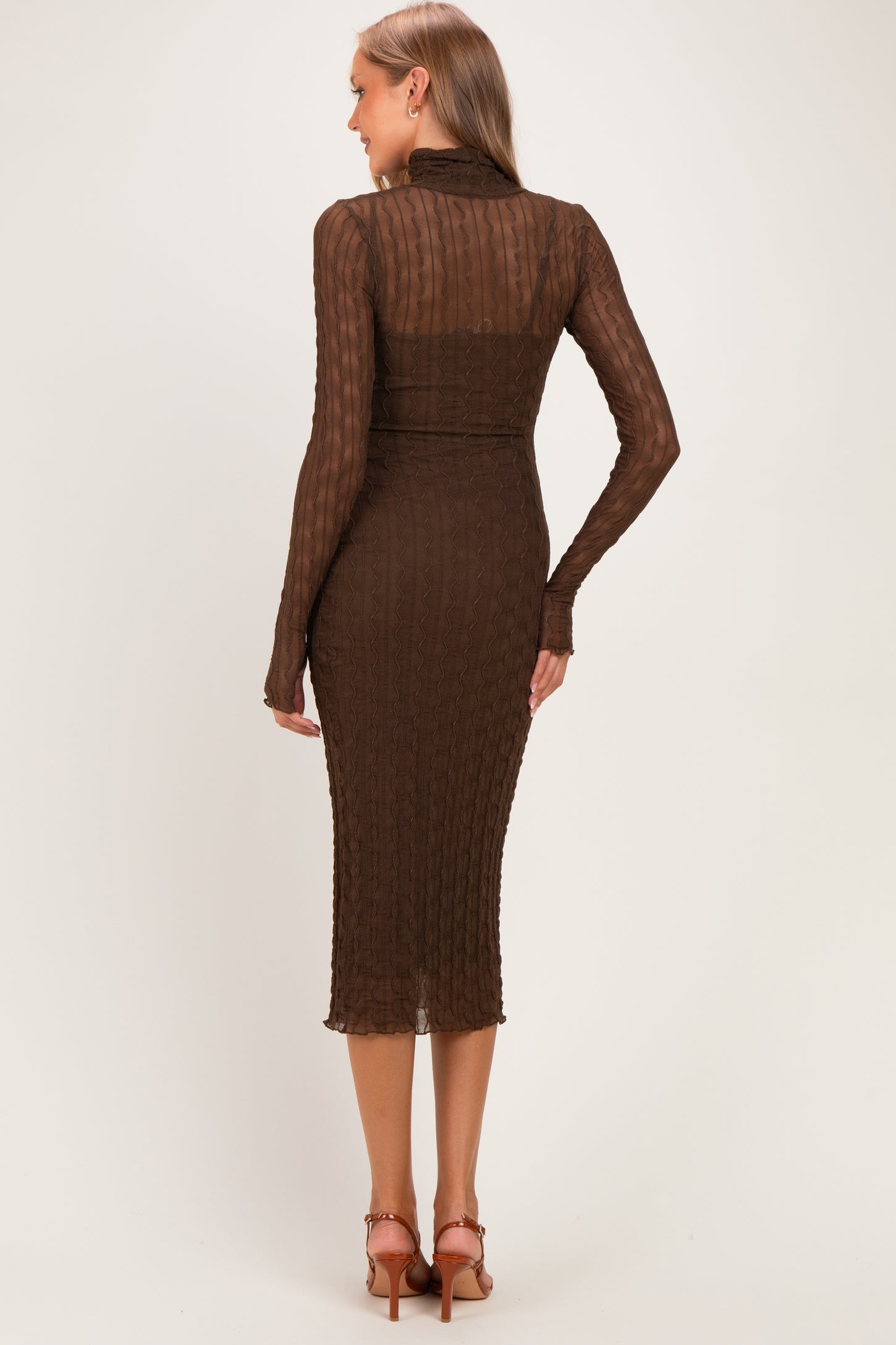 woman wearing a brown ribbed maternity dress with long sleeves and a fitted silhouette, showing the back view