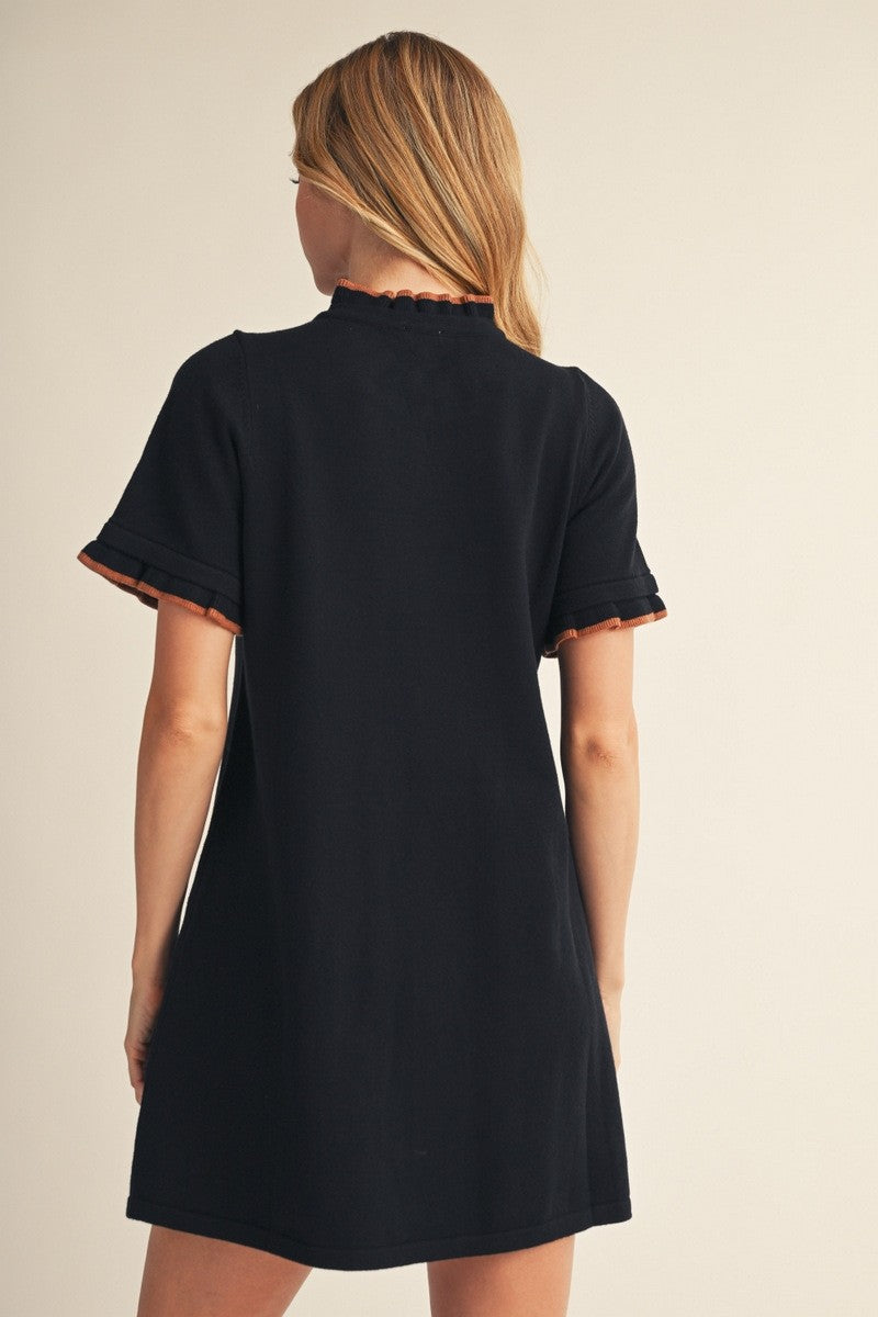woman wearing a black short sleeve dress with scalloped detailing on the sleeves