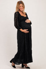woman wearing a black lace maternity maxi dress and holding her baby bump