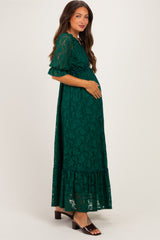 woman wearing a green lace maternity maxi dress and holding her baby bump