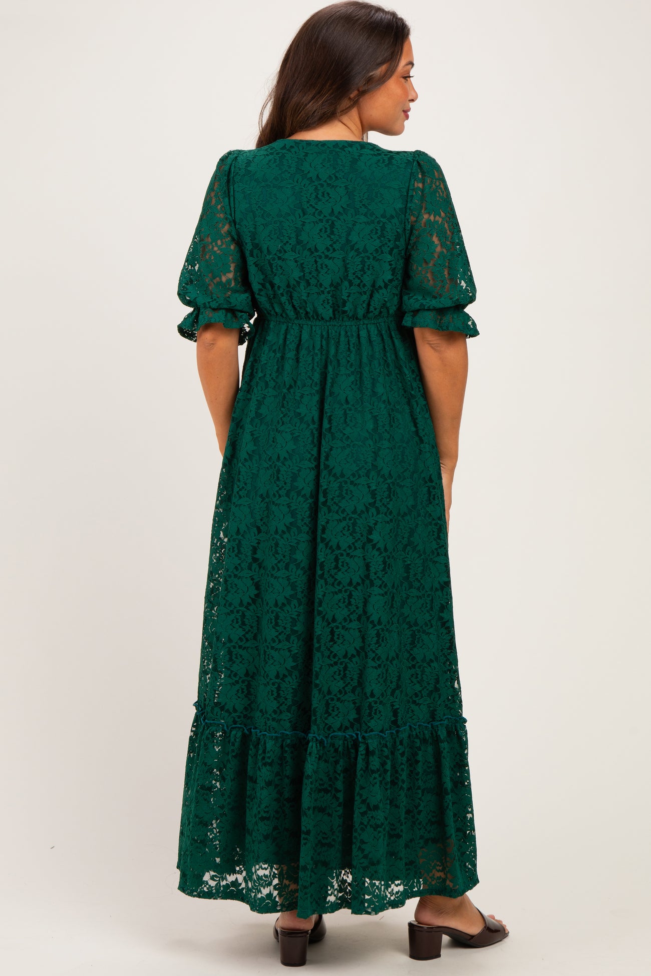 woman wearing a green lace maternity dress with puff sleeves and a tiered skirt, shown from the back