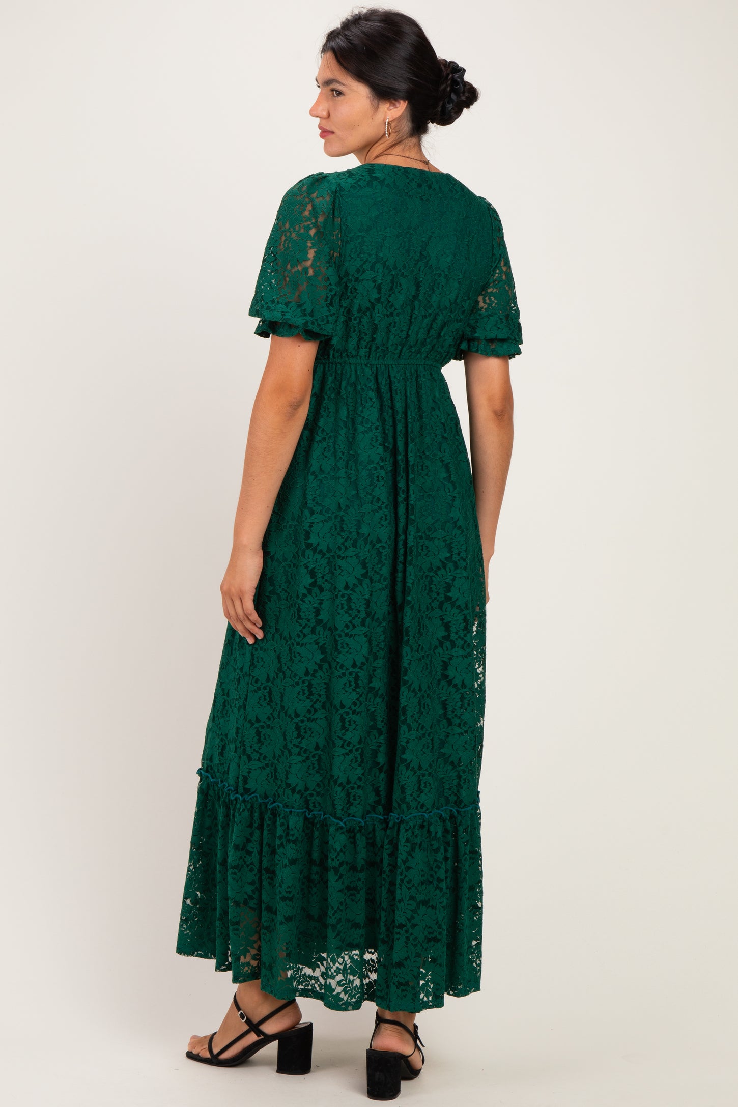 woman wearing a dark green lace maxi dress with short sleeves and a tiered hem, shown from the back