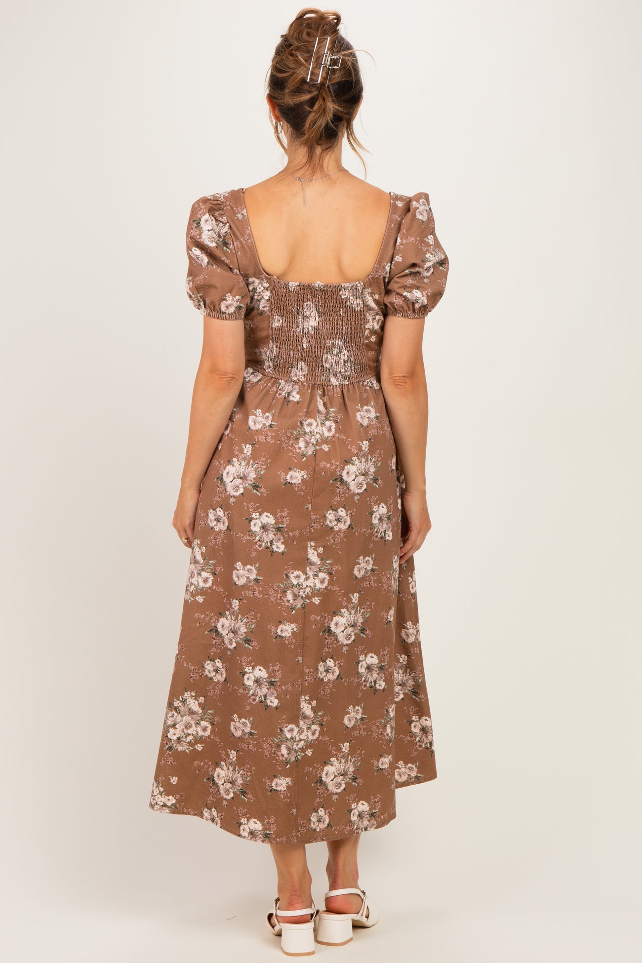 woman wearing a brown floral maternity dress with puff sleeves and smocked back, showing a baby bump