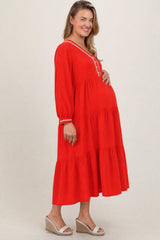 woman wearing a red tiered maternity maxi dress with embroidery and a visible baby bump