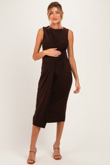 woman wearing a brown maternity dress with a twisted bodice and knee-length skirt, holding her baby bump