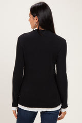 woman wearing a black ribbed long sleeve top with a white layered hem, seen from the back