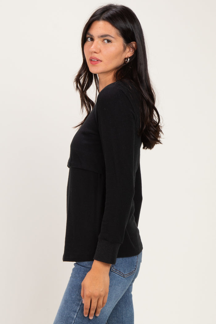 woman wearing a black long sleeve top with a relaxed fit and side view, paired with blue jeans