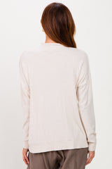 woman wearing a beige oversized sweater with long sleeves and a relaxed fit, viewed from the back