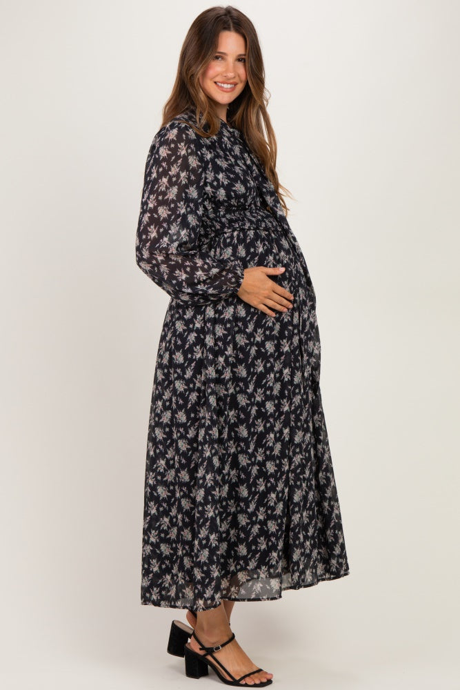 woman wearing a black floral long sleeve maternity dress and holding her baby bump