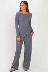woman wearing a gray long sleeve henley top and matching wide-leg pants, posing with one hand in her pocket