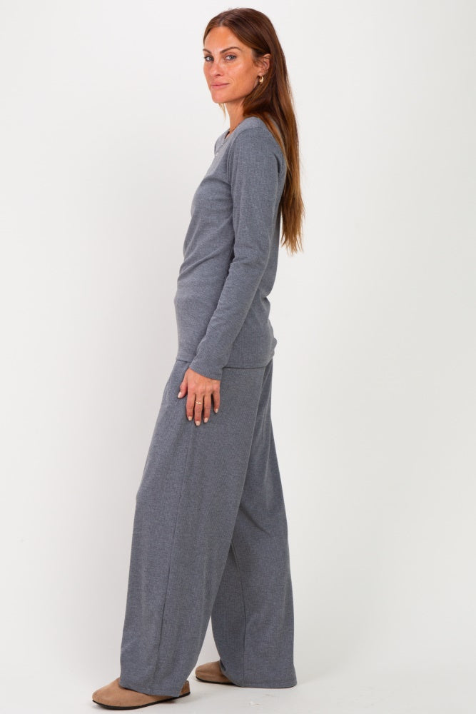 woman wearing a grey long sleeve top and wide-leg pants, standing sideways with a relaxed pose