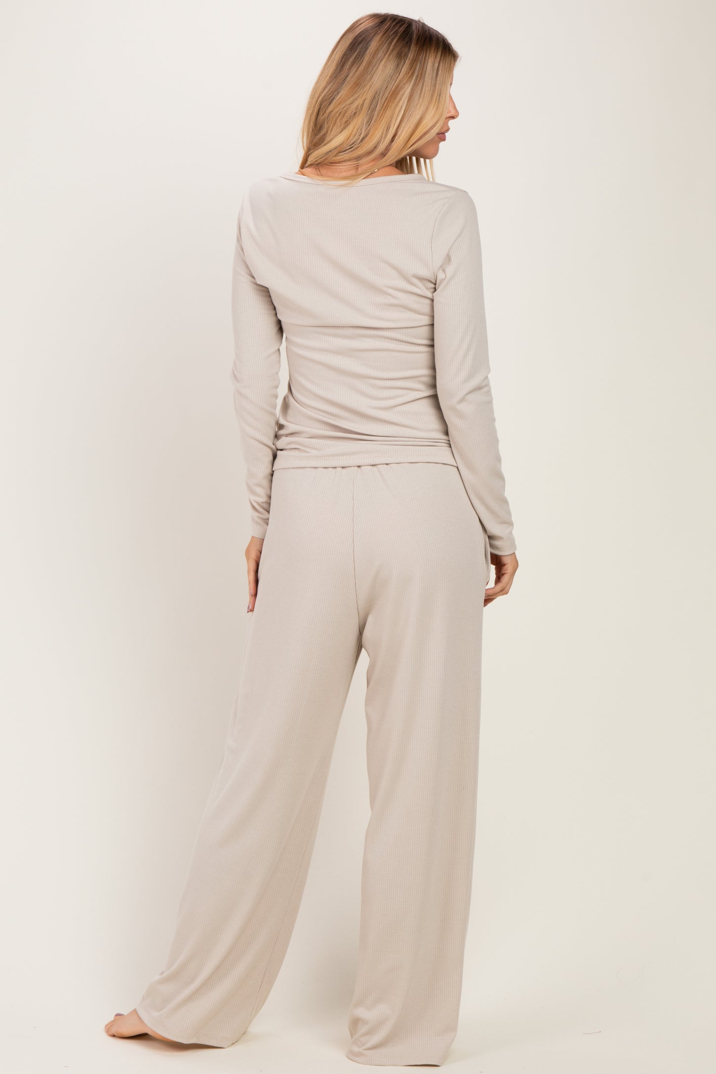 woman wearing a beige long sleeve top and matching wide-leg pants, seen from the back