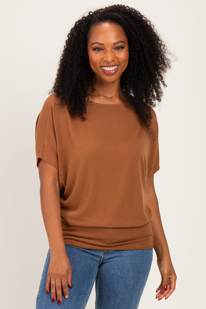 woman wearing a brown short sleeve top with a relaxed fit and smiling at the camera