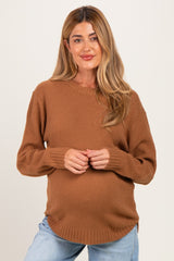 woman wearing a brown knit maternity sweater with a relaxed fit and round neckline, showing her baby bump