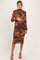 woman wearing a floral print long sleeve maternity dress with ruching and holding her baby bump