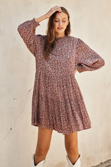woman wearing a pink floral long sleeve mini dress with gathered skirt and round neckline