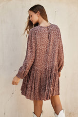 woman wearing a dusty rose floral long sleeve dress with a flared skirt and button detail at the back