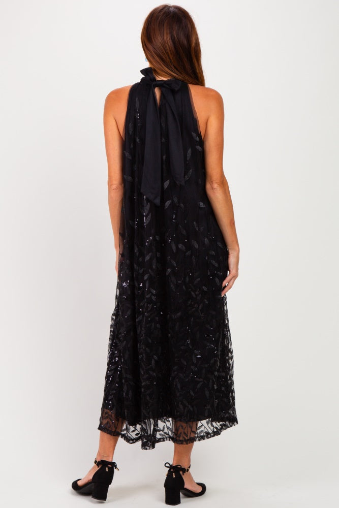 woman wearing a black maxi dress with a halter neck and sequin details, showing the back view
