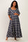woman wearing a navy plaid maternity maxi dress with puff sleeves and pockets, holding her baby bump