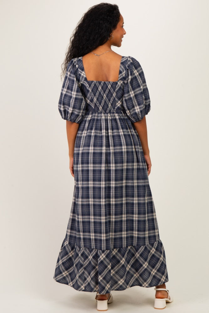 woman wearing a navy plaid maternity maxi dress with puff sleeves and a smocked bodice