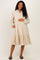 woman wearing a cream floral maternity dress with a tiered skirt and pockets, holding her baby bump