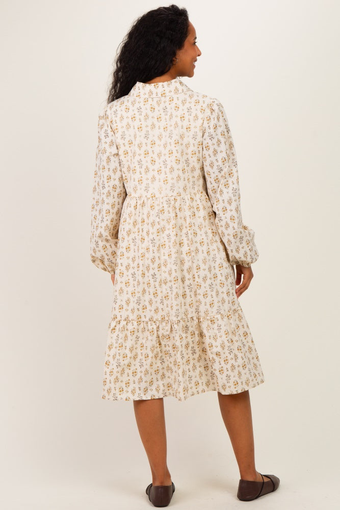woman wearing a floral print maternity dress with long sleeves and a tiered skirt, showing her back