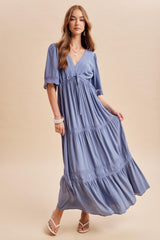 woman wearing a light blue tiered maxi dress with short sleeves and lace details standing in a relaxed pose