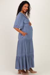 woman wearing a blue maternity maxi dress with short sleeves and pockets, showing her baby bump