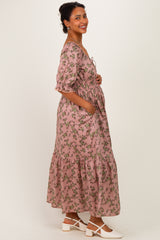 woman wearing a floral pink maternity dress with a tiered skirt and pockets, showing her baby bump