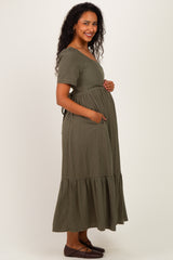 woman wearing a green striped maternity maxi dress with short sleeves and pockets, showing her baby bump