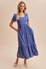 woman wearing a blue ribbed short sleeve midi dress with a square neckline and side pockets