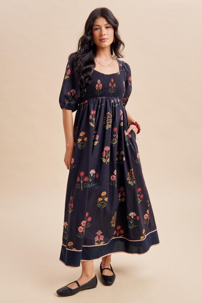 woman wearing a black floral smocked maxi dress with puff sleeves and a flowing skirt