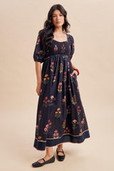woman wearing a black floral smocked maxi dress with puff sleeves and a flowing skirt