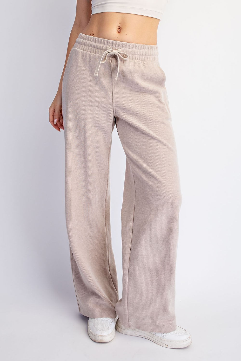 woman wearing beige wide-leg lounge pants with an elastic waistband and drawstring detail