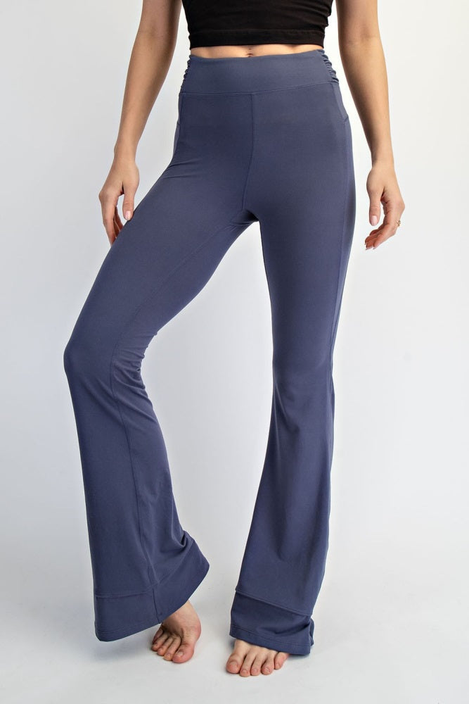 woman wearing navy blue flared yoga pants with a high waistband, standing barefoot against a white background