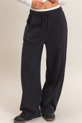 woman wearing black wide-leg lounge pants with an elastic waistband and side pockets