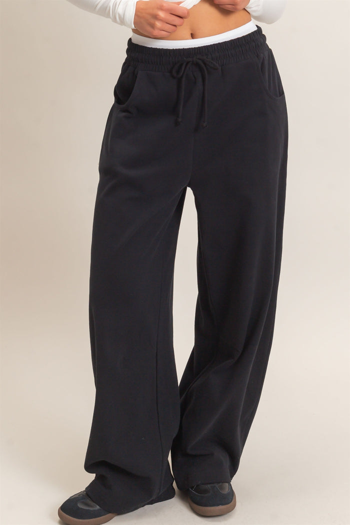 woman wearing black wide-leg lounge pants with an elastic waistband and side pockets