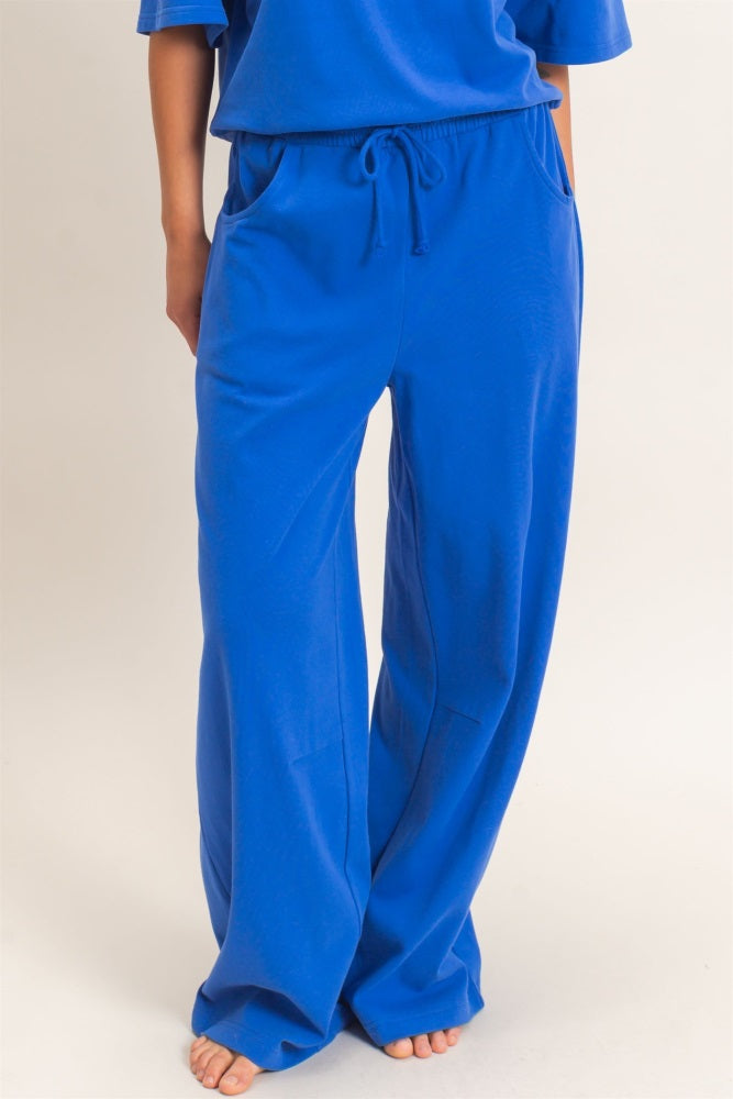 woman wearing bright blue loose-fitting lounge pants with side pockets and drawstring waistband