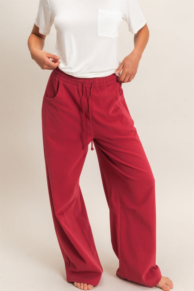 woman wearing red relaxed fit pants with pockets and a white short sleeve top