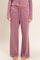 woman wearing a mauve loungewear set with long sleeve top and wide-leg pants, standing barefoot