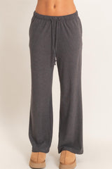 woman wearing dark gray wide leg lounge pants with an elastic waistband and drawstring detail