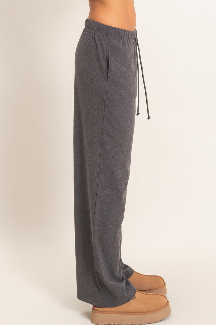 woman wearing dark gray sweatpants with a drawstring waist and side pockets, standing sideways