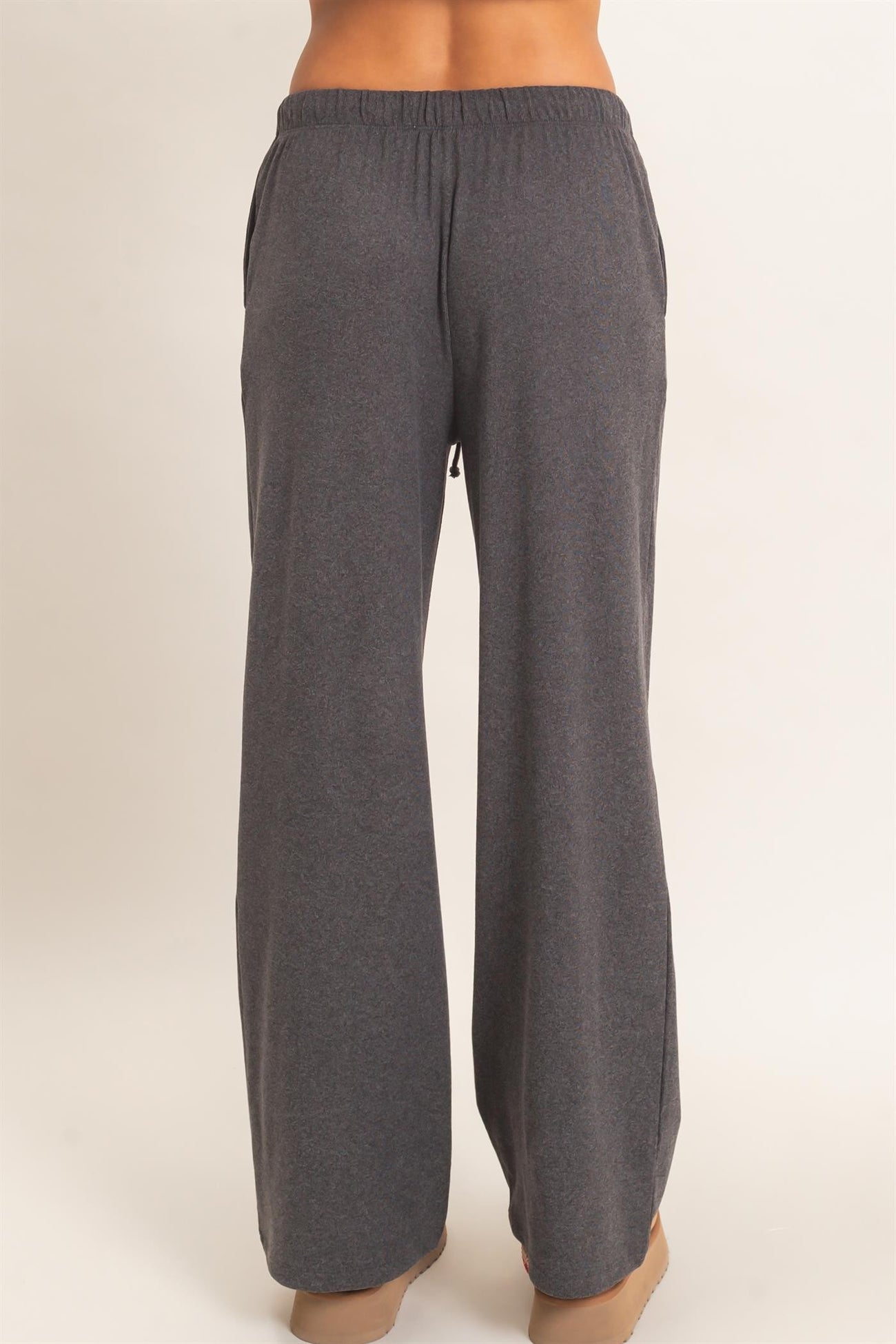 woman wearing dark gray wide-leg sweatpants with an elastic waistband and side pockets, shown from the back