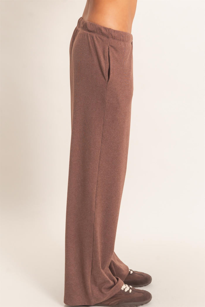woman wearing brown wide-leg lounge pants with side pockets and an elastic waistband