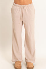 woman wearing light beige relaxed fit lounge pants with an elastic waistband and drawstring
