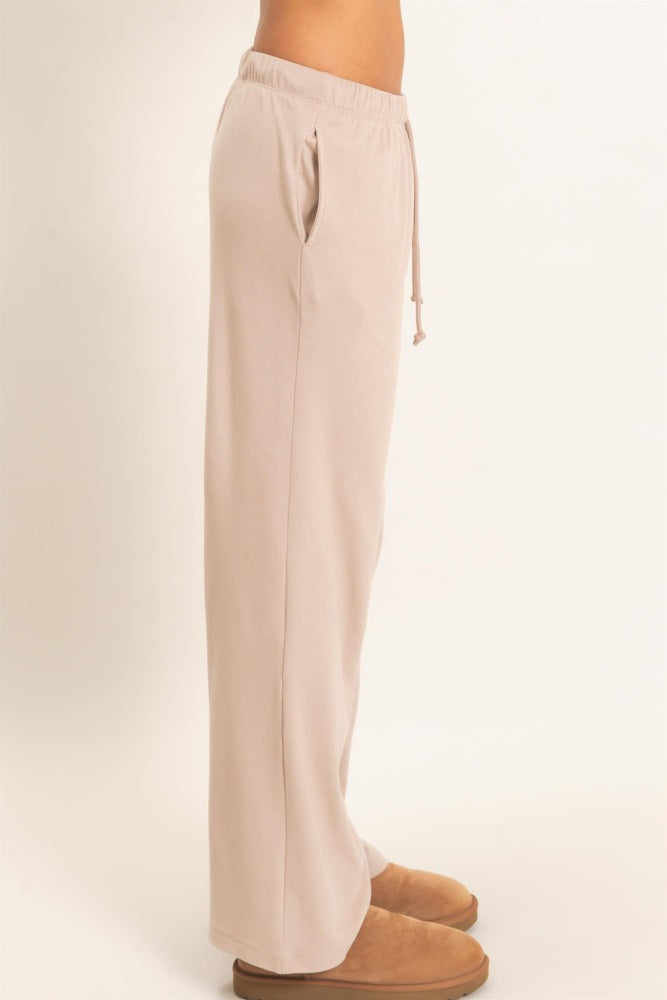 woman wearing light beige wide-leg lounge pants with side pockets and drawstring waist