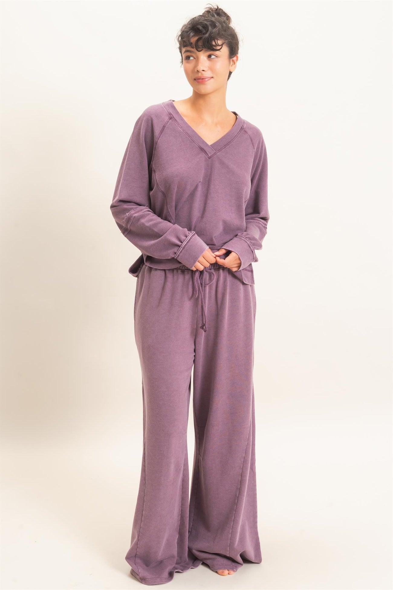 woman wearing a purple long sleeve loungewear set with a v-neck and drawstring pants