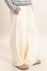 woman wearing cream wide-leg lounge pants with side pockets and a drawstring waistband